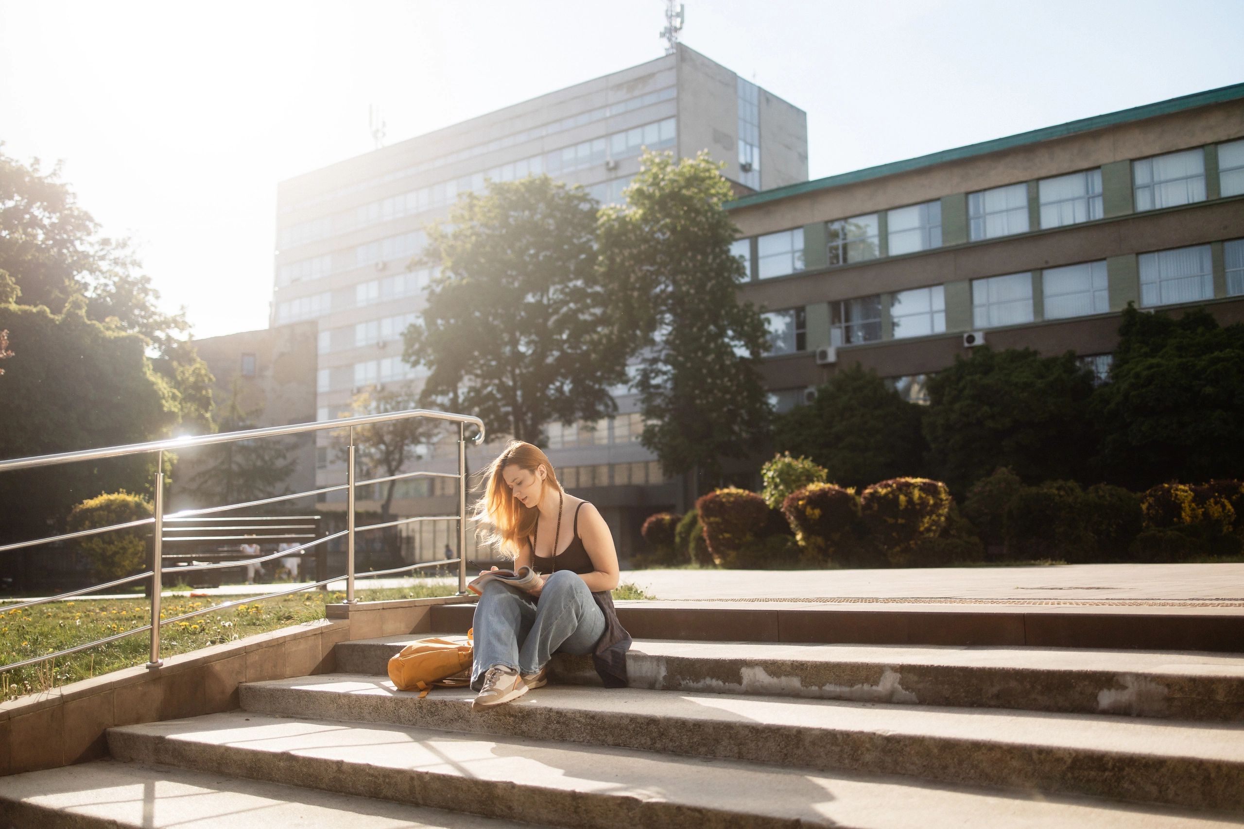 Student reading and studying on university campus steps
